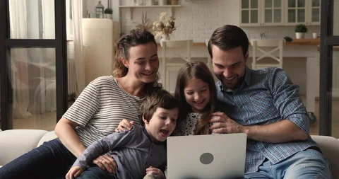 Happy young couple parents using computer with small kids. Video stock 156313700