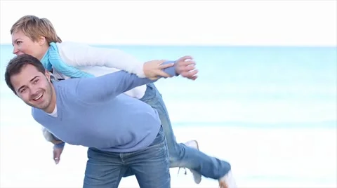 Happy young couple piggibacking on the beach Stock Footage 46025174