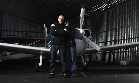 Happy young couple posing in front of private airplane beautiful and happy... Stock Photos