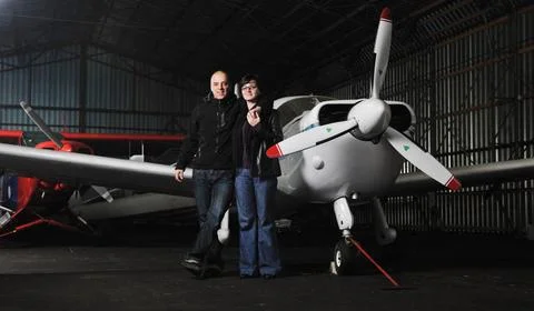 Happy young couple posing in front of private airplane beautiful and happy... Stock Photos