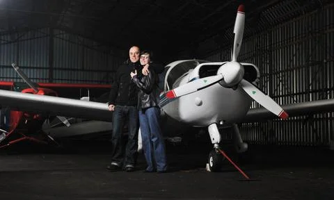 Happy young couple posing in front of private airplane beautiful and happy... Stock Photos