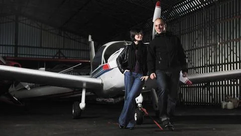 Happy young couple posing in front of private airplane beautiful and happy... Stock Photos