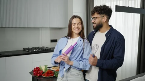 Happy young couple posing with kitchen utensils at home Video stock 335333900