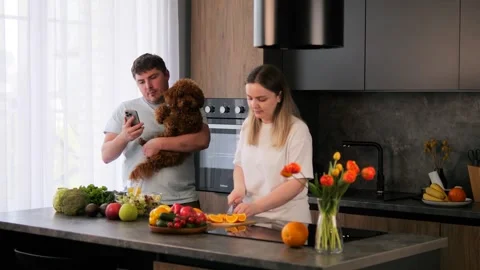 Happy young couple preparing delicious breakfast in home kitchen in company Stock Footage 277109467