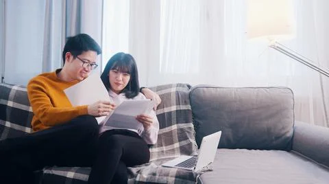 Happy young couple relaxing on the couch and looking at papers Stock Photos