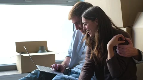 A happy young couple sits surrounded by moving Stock Footage 332685490