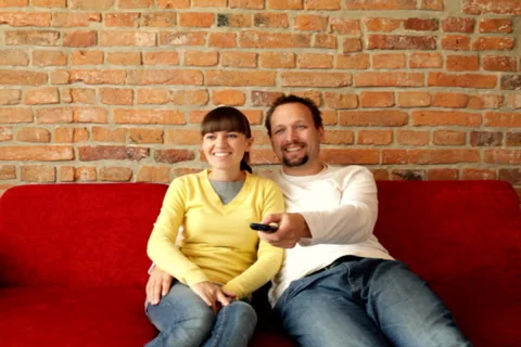 Happy young couple sitting on sofa and watching tv Stock Footage 1180948