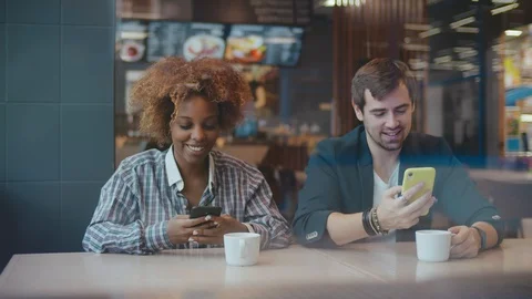 Happy young couple spending time at the cafe indoors, using mobile phones Stock Footage 123471191