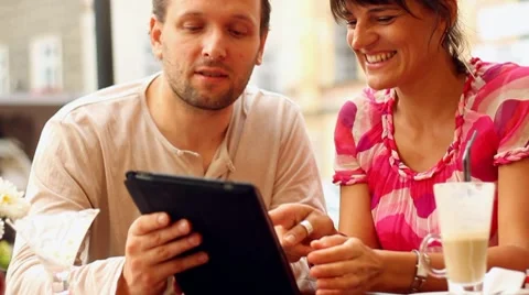 Happy young couple with tablet computer in restaurant, outdoors HD Stock Footage 8667306