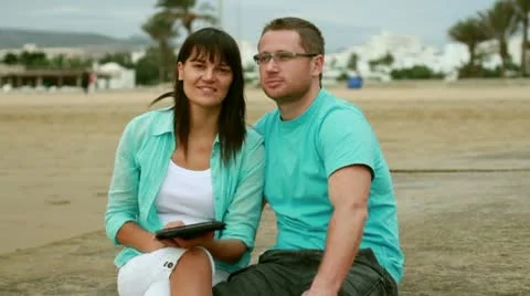 Happy young couple with tablet computer on the beach Видео 10758042