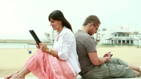 Happy young couple with tablet computer and cellphone on the beach Stock Footage 10763922