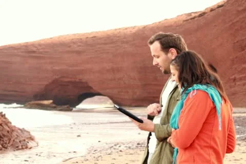 Happy young couple with tablet computer on beautiful Legzira beach NTSC Stock Footage 10826632