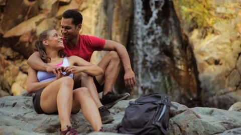 Happy young couple take a break from their hike to sit and chat and snuggle Vidéo 88404807