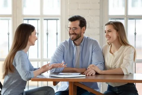 Happy young couple talk with realtor at meeting Stock Photos