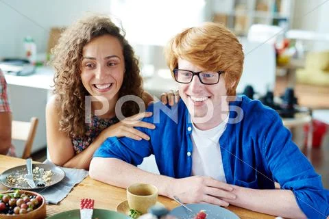 Happy young couple talking to friends by festive table Stock Photos