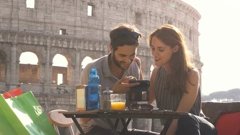 Happy young couple tourists using smartphone sitting at bar restaurant in front Stock Footage 85660098