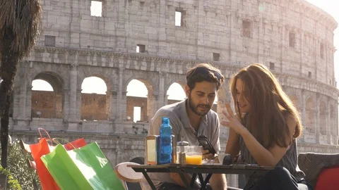 Happy young couple tourists using smartphone sitting at bar restaurant in front 스톡 동영상 90666151