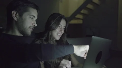 Happy young couple using laptop together at home 動画素材 100547956