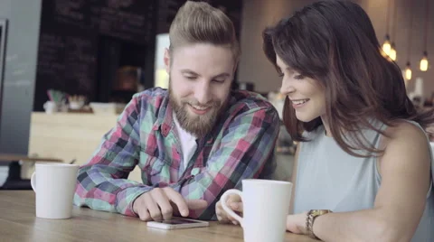 Happy young couple using phone at cafe Stock Footage 64653164