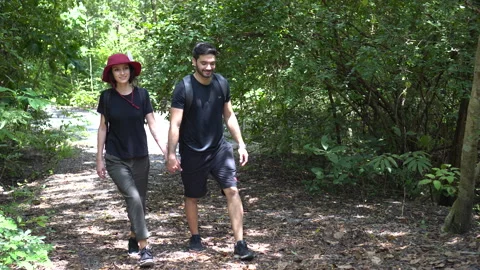 Happy young Couple walking through forest in nature park together . Young gir Stock Footage 163691347