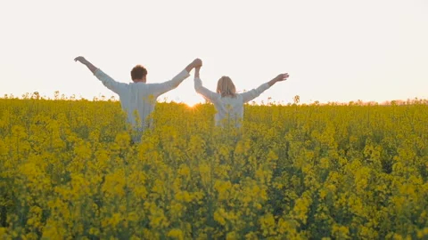 Happy young couple in yellow rape flowers field during sunset Video stock 89425986