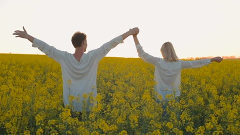 Happy young couple in yellow rape flowers field during sunset Video stock 89426541