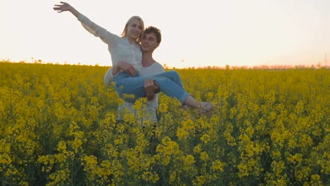 Happy young couple in yellow rape flowers field during sunset Vidéo 89427104