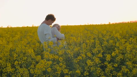 Happy young couple in yellow rape flowers field during sunset Vidéo 89427196