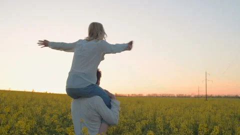 Happy young couple in yellow rape flowers field during sunset Видео 89427716