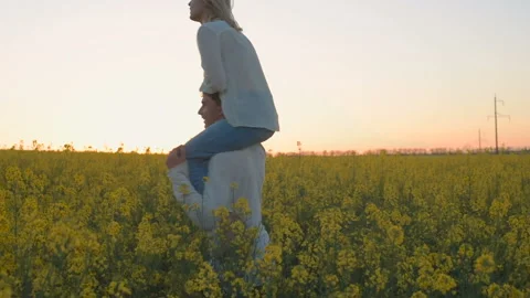 Happy young couple in yellow rape flowers field during sunset Vídeo Stock 89428529