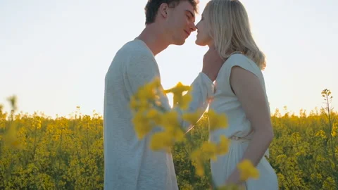 Happy young couple in yellow rape flowers field during sunset Stock Footage 89436638