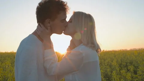 Happy young couple in yellow rape flowers field during sunset Stock Footage 89456786