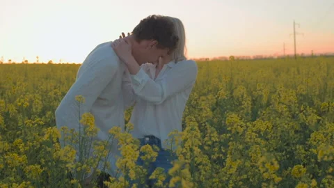 Happy young couple in yellow rape flowers field during sunset Stock Footage 89457053