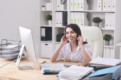 Happy young customer support representative with headset looking at client Stock Photos