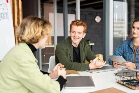 Happy young developer of mobile applications talking to one female colleagues Stock Photos