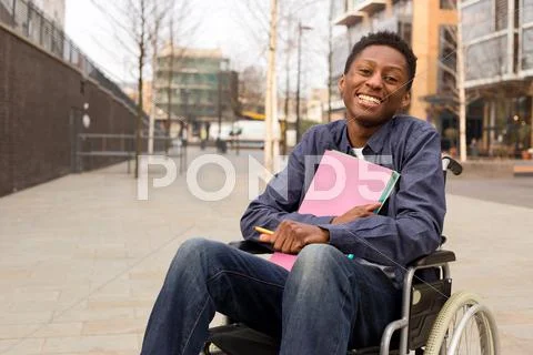 Happy young disabled man in a wheelchair holding folders. Stock Photos
