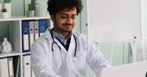 Happy young doctor smiling while using laptop at office Video stock 196074959