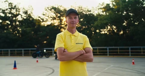 Happy young driving instructor in yellow t-shirt. The guy poses with his arms Stock Footage 249435549