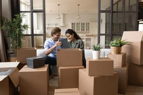 Happy young family couple homeowners unpacking belongings. Stock Photos