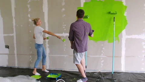 Happy young family dancing with the rollers and brushes during the repair of the Stock Footage 137290902