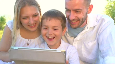 Happy young family with kid using tablet pc in summer park Stock Footage 59081087