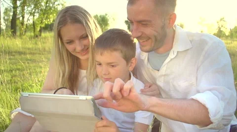 Happy young family with kid using tablet PC in summer park Stock Footage 59082728