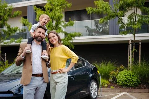 Happy young family with little son waiting for charging their electric car. Stock Photos