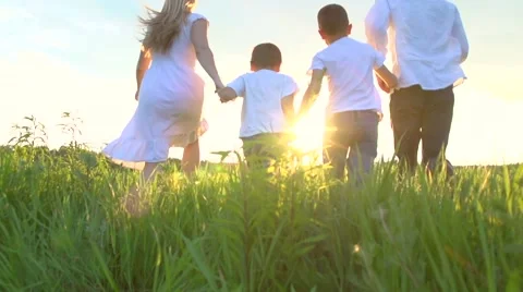 Happy young family with two children running on summer field Stock Footage