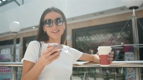 Happy young fashionable woman taking a coffee break after shopping, smiling with Stock Footage