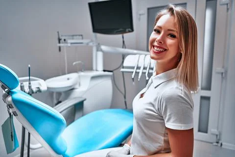 Happy young female dentist with tools over medical office background Stock Photos