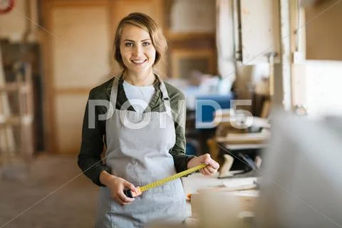 Happy young female in uniform of carpenter looking at camera Stock Photos
