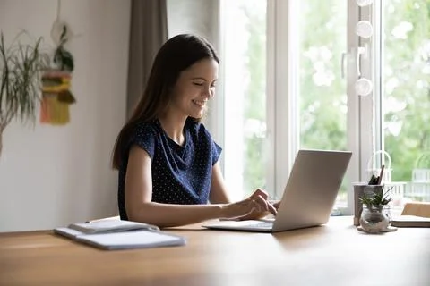 Happy young freelance worker using laptop at home Stock Photos