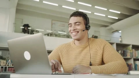 Happy young friendly multi racial man in eyeglasses wearing headset with mic Stock Footage 154376256