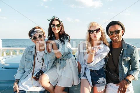 Happy young friends standing and sending kiss outdoors Stock Photos